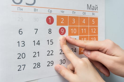 Child and adult hands indicate the date of May 9 wall calendar