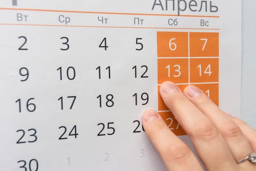 Fingers point to the weekend in the wall calendar