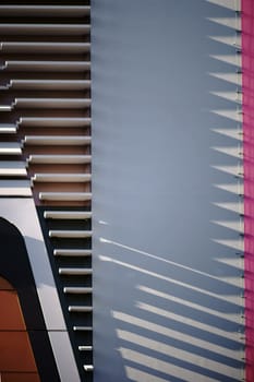 The modern facade of a shopping building with abstract cladding casts shadows...