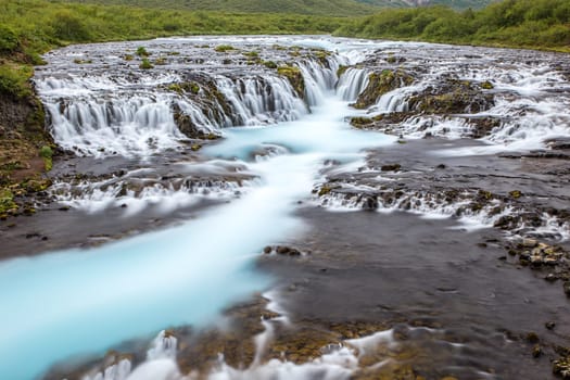 Bright powerful Bruarfoss waterfall in Iceland with cyan water blurred by long exposure. Popular tourist attraction. Unusual and picturesque scene. Location place South Iceland, Europe. Artistic picture. Beauty world.