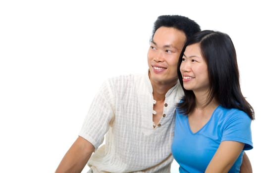 Young Asian couple sitting on sofa with smiling face, looking at side, on white background.