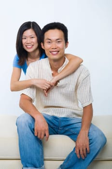 Young Asian couple sitting on sofa with smiling face, on white background.