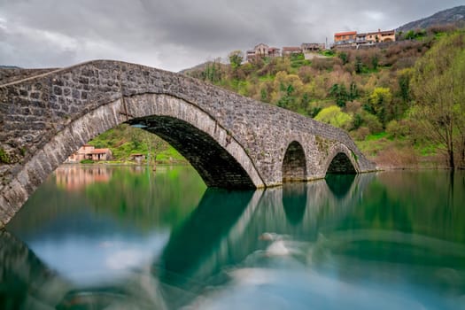 Small ancient stone arch bridge  in Rijeka Crnojevica on a rainy day, Montenegro
