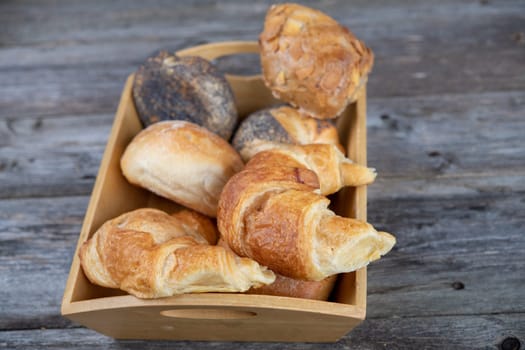 different fresh rolls and croissants in wooden basket