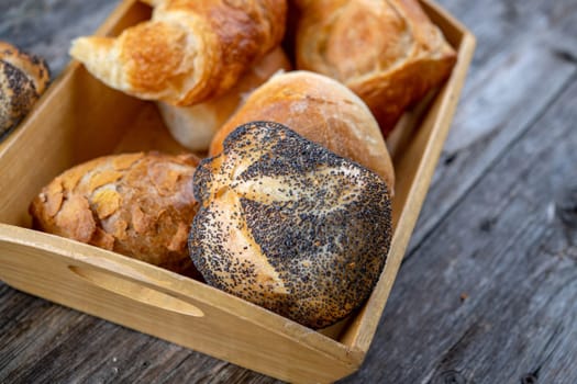 different fresh rolls and croissants in wooden basket in top view