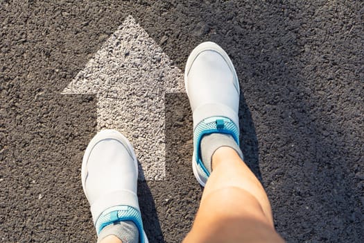 Top view of man wearing white shoes choosing a way marked with white arrows. Chooses the right path concept.
