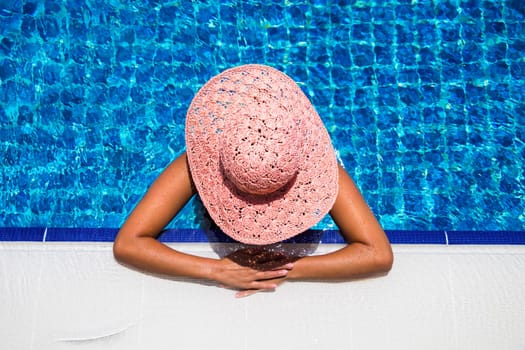 Beautiful young woman in the swimming pool on a sunny summer day