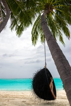 Beautiful woman relaxes on a swing on the dream beach