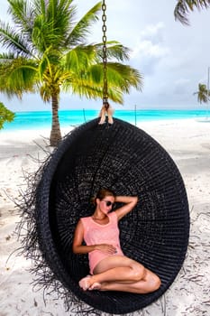 Beautiful woman relaxes on a swing on the dream beach