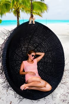 Beautiful woman relaxes on a swing on the dream beach