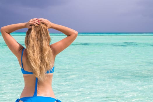 Blonde Girl in blue bikini in the turquoise sea