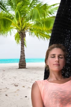Beautiful woman relaxes on a swing on the dream beach