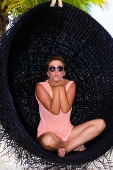 Beautiful woman relaxes on a swing on the dream beach