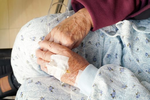 Close up of elderly woman hands with intravenous drip on a wheelchair at hospital