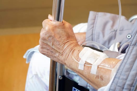 Close up of elderly woman hands with intravenous drip on a wheelchair
