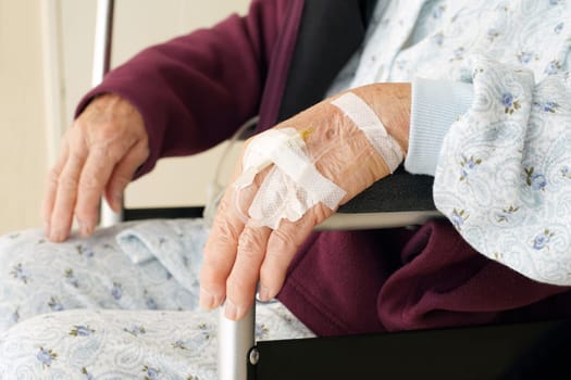 Close up of elderly woman hands with intravenous drip on a wheelchair