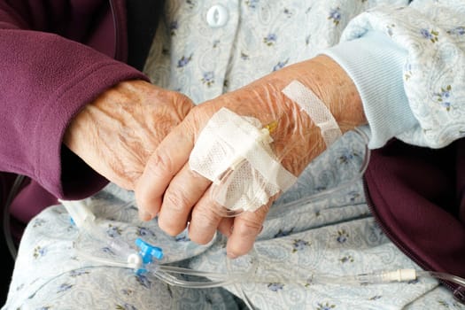 Close up of elderly woman hands with intravenous drip on a wheelchair