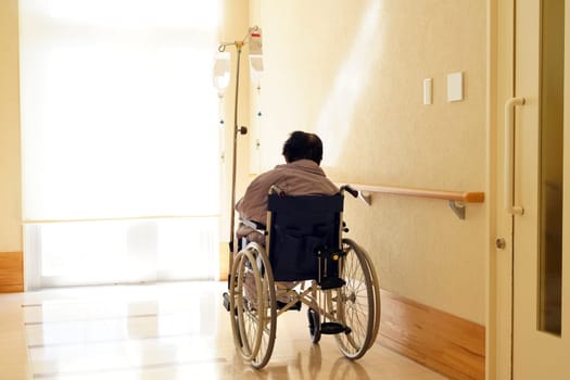 Back view of senior or elderly woman on wheelchair at hospital hallway