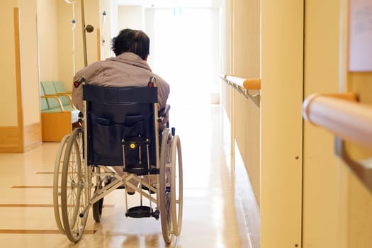 Back view of senior or elderly woman on wheelchair at hospital hallway