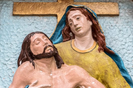 Religious stone statue in color representing The Pity of Michelangelo. Mary mother holding Jesus Christ on her lap after the Crucifixion.