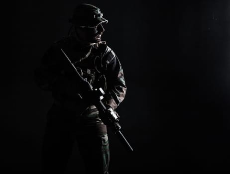 Bearded Special forces United States in Camouflage Uniforms studio shot half length. Holding weapons, wearing jungle hat, Shemagh scarf, he is ready to kill. Contour shot, backlit
