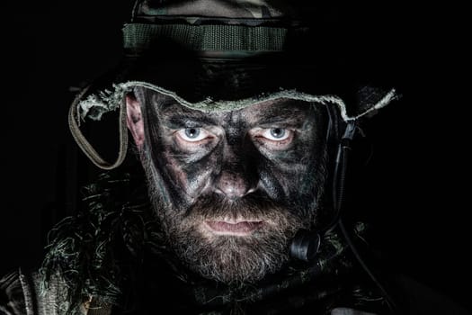 Special forces United States in Camouflage Uniforms studio shot. Wearing jungle hat, Shemagh scarf, painted face. Black background, bottom light
