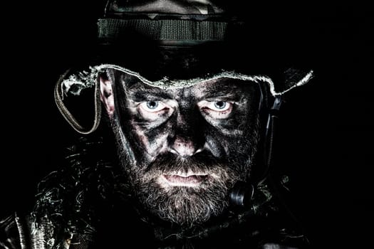 Special forces United States in Camouflage Uniforms studio shot. Wearing jungle hat, Shemagh scarf, painted face. Black background, bottom light