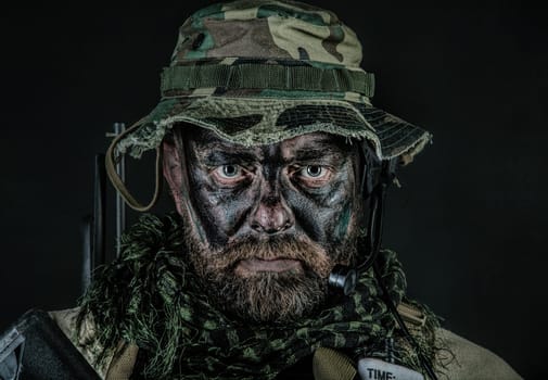 Special forces United States in Camouflage Uniforms studio shot. Wearing jungle hat, Shemagh scarf, painted face. Black background