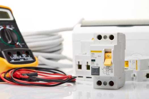 Automatic circuit breakers, distribution box, cable and digital tester on a white background. Electrical equipment. Accessories for electrical protection and control