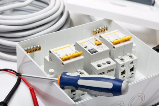 Automatic circuit breakers, distribution box, cable and screwdriver on a white background. Electrical equipment. Accessories for electrical protection and control