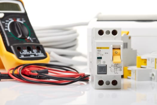 Automatic circuit breakers, distribution box, cable and digital tester on a white background. Electrical equipment. Accessories for electrical protection and control