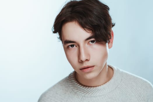 Studio portrait young man in grey sweater on white background.
