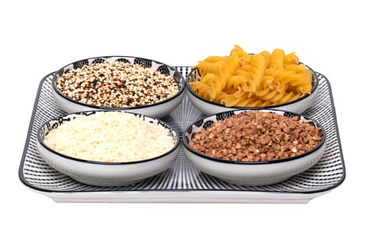 Vegetable food. Macro of a decorative plate with four bowls with buckwheat, noodles, rice and quinoa isolated on a white background. Healthy eating.