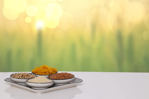 Table top on vegetable food background. Four bowls with buckwheat, noodles, rice and quinoa on a white table over abstract bright green yellow summer backdrop. Template for display product montage.