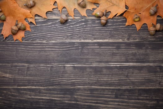 Autumn oak leaves and acorns on wooden table. Copy space. Top view