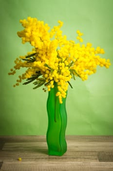 Spring bouquet of mimosa in a green vase