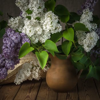 Still-life with a bouquet of lilacs and a straw hat, close-up
