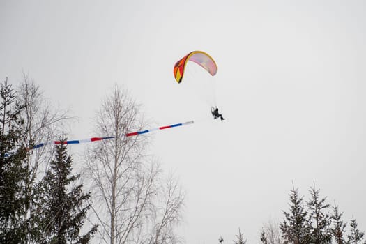 Paraglider is flying in the sky in the Altai winter mountains.