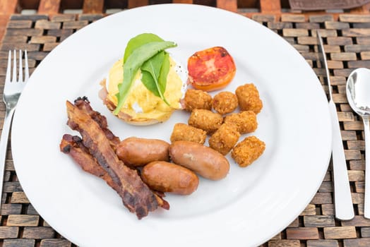 Delicious breakfast with eggs Benedict, bacon, sausage, and potato hash brown
