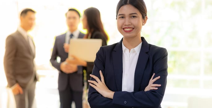 Portrait of asian businesswoman with business team in background at office window using for coporate working background, panoramic web banner composition