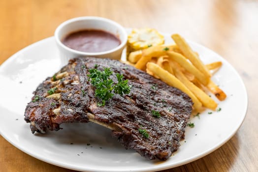 Grilled Barbecued Pork Baby Back Ribs with grilled sweet corn and fries