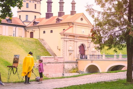 NESVIZH, BELARUS - JUNE 12, 2014: Old medieval castle in Nesvizh, Belarus, Europe. Young woman and girl with castle painting.