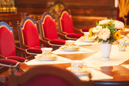 Dining room of medieval castle in Belarus. Old beatiful red chairs and table with flowers