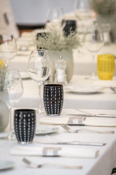 Wine glasses, coffee plates and cutlery on the table before the start of the service in the restaurant