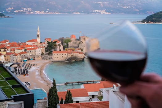 Woman holding glass with red wine on the balcony of her apartment in the Budva town, Montenegro