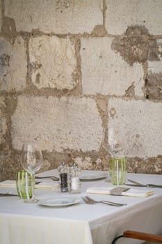 Wine glasses, coffee plates and cutlery on the table before the start of the service in the restaurant