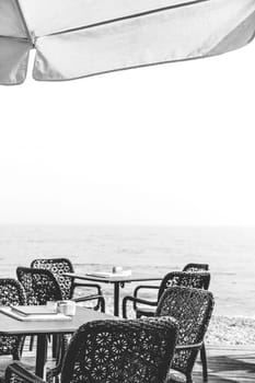 Wicker chairs by the empty outdoor restaurant tables at a seaside resort in summer