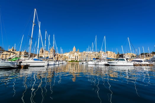 Water level  view of boats with a cityscape of Birgu, one of the Three Cities, in Malta