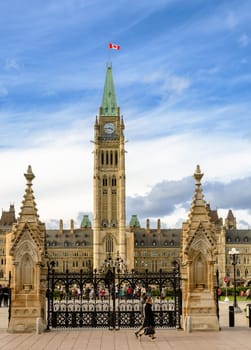 Ottawa, Canada - October 14, 2018 : Unidentified tourist walking in front of Parliament Hill in Ottawa, Canada. Facade view of Centre Block of Canadian Parliamentary complex.