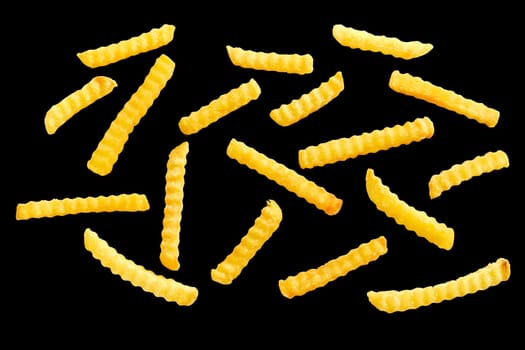 Pieces of fusilli pasta spread individually on black background